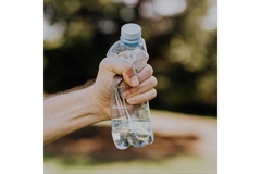 Squeezing small plastic beverage bottle.